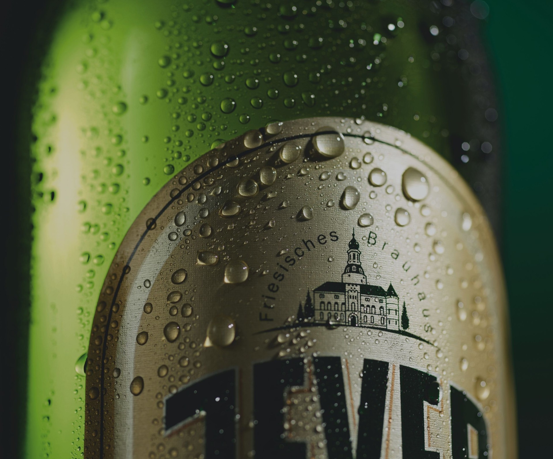 Nahaufnahme eines grünen Bierflaschenetiketts mit Tautropfen darauf.