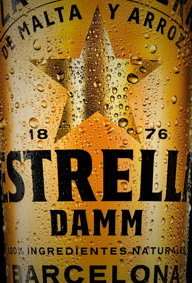 Nahaufnahme eines Bieretiketts mit Wassertropfen einem Stern und einem Schriftzug Estrella Damm.