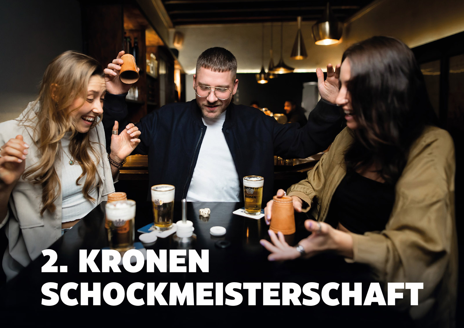 Drei Personen lachen und spielen ein Trinkspiel in einer Bar.
