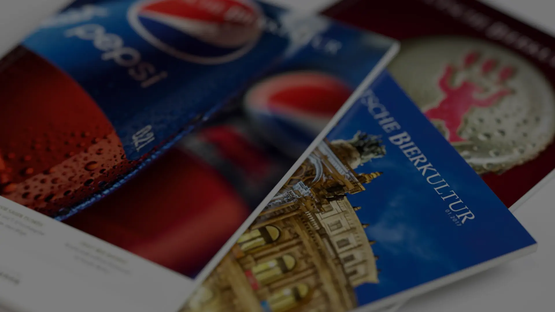 Drei unterschiedliche Magazine liegen überlappend auf einem Tisch.