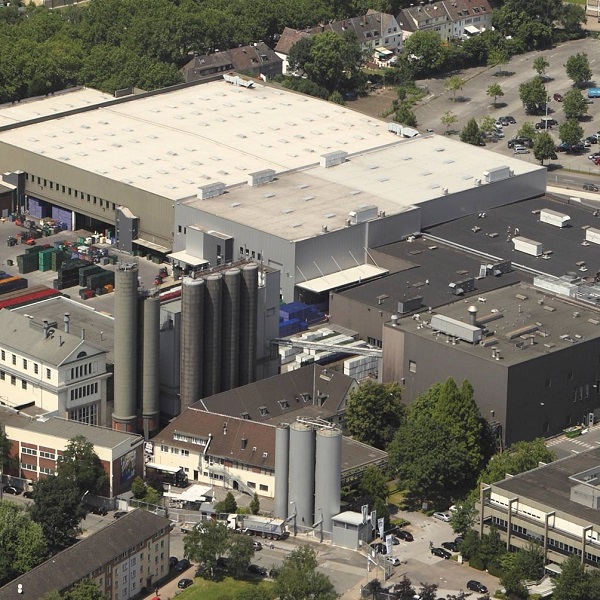 Ein Luftbild zeigt ein großes Industriegelände mit mehreren Hallen und Silos.