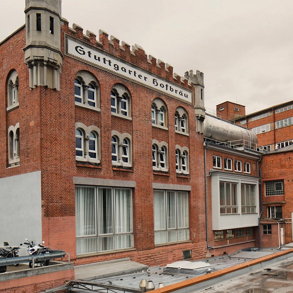 Ein historisches rotes Backsteingebäude mit Zinnen steht neben moderneren Strukturen.
