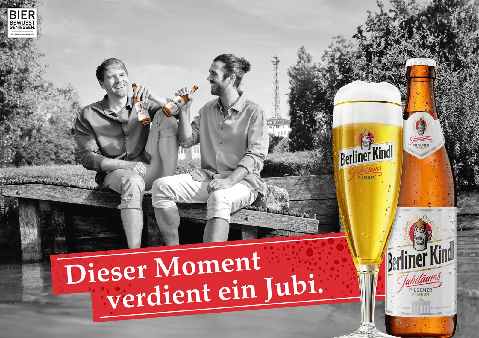 Zwei Männer lachen und halten Flaschen, während sie auf einer Brücke sitzen.