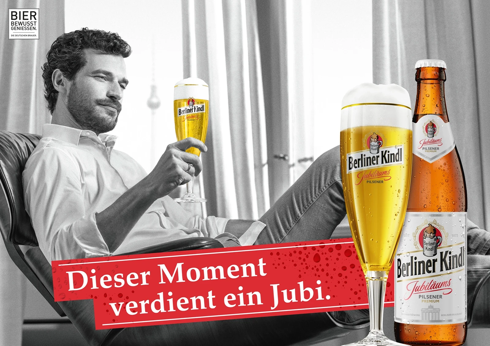 Ein Mann sitzt lächelnd mit einem gefüllten Bierglas in der Hand. Er lehnt sich in einem Sessel zurück und schaut das Glas an.