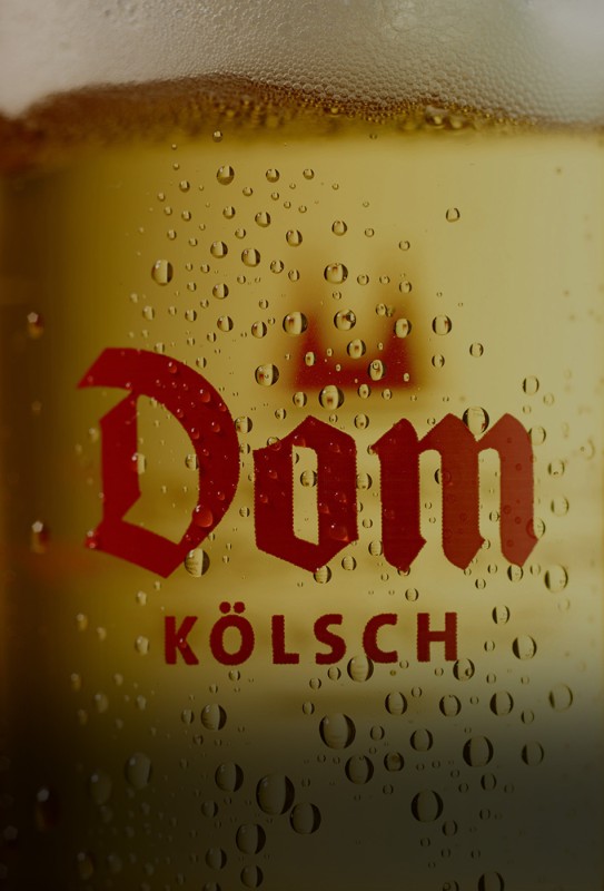 Ein Glas gefüllt mit hellem Bier, bedeckt von kondensierten Wassertröpfchen.