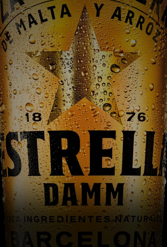 Nahaufnahme eines Bieretiketts mit Wassertropfen einem Stern und einem Schriftzug Estrella Damm.