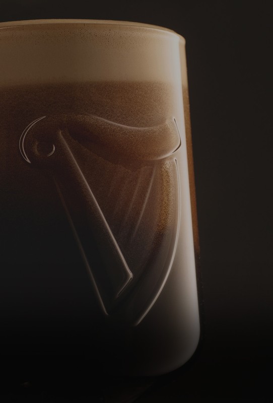 Ein dunkles Bier füllt ein Glas, dessen Schaum oben schaumig ist und das Glas glänzt sanft.