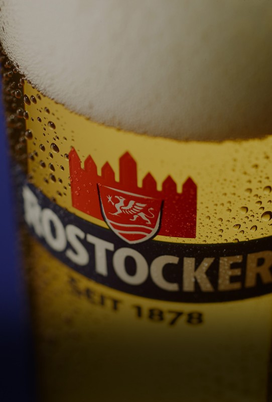 Nahaufnahme eines Glas mit Bierschaum und sichtbaren Kondenswassertröpfchen auf der Oberfläche.