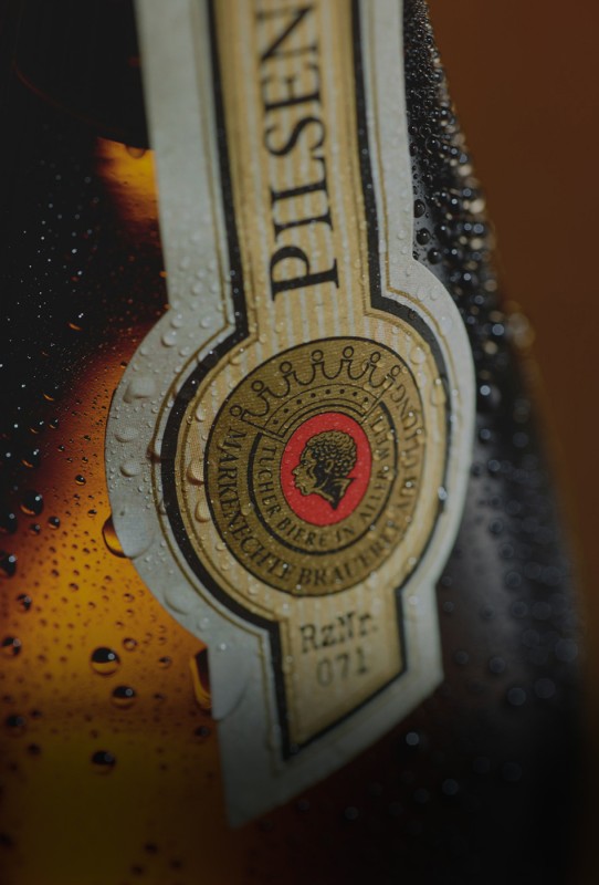Nahaufnahme eines Bierflaschenetiketts mit Wassertropfen und Prägedetails.