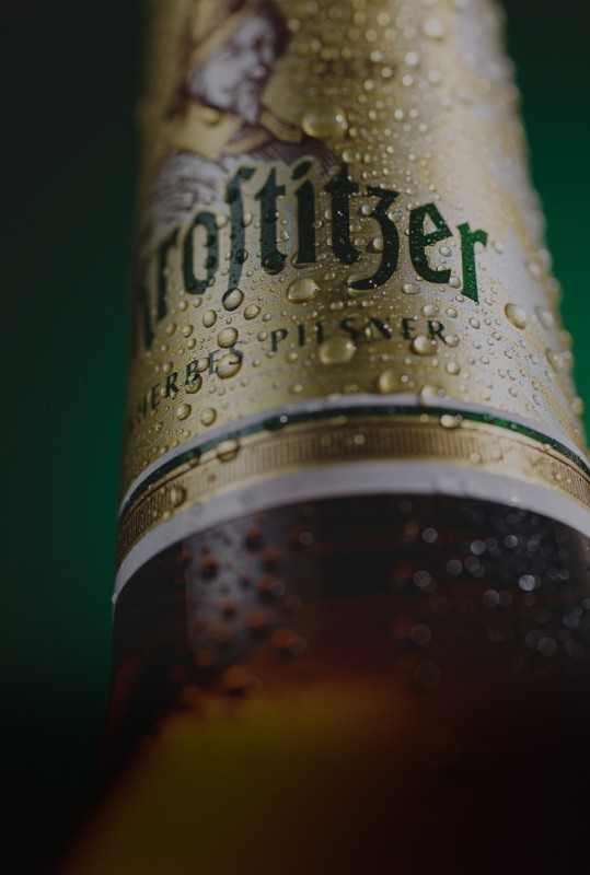 Nahaufnahme einer Bierflasche mit Kondenswasser und Schriftzug.