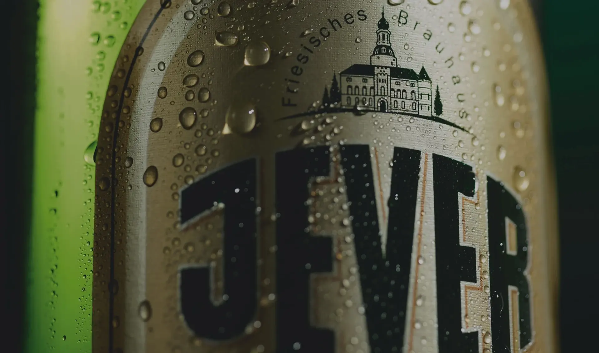 Nahaufnahme eines grünen Bierflaschenetiketts von Jever mit Tautropfen darauf.