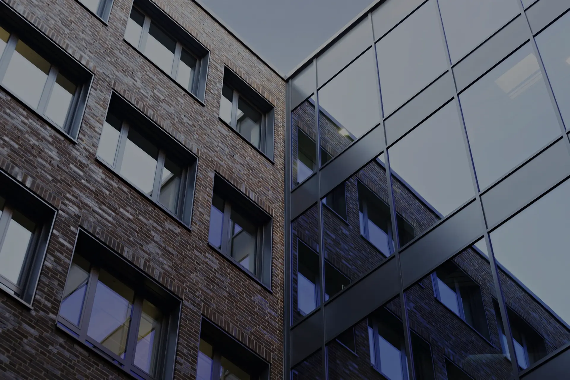 Ein modernes Gebäude mit Backsteinfassade und Glasfronten spiegelt das Sonnenlicht.