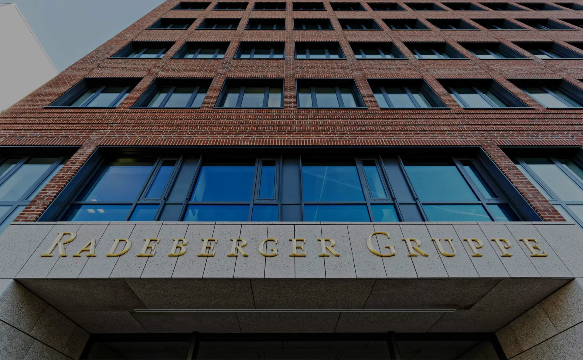 A multi-story office building with a red brick facade and the words “Radeberger Group” above the entrance.