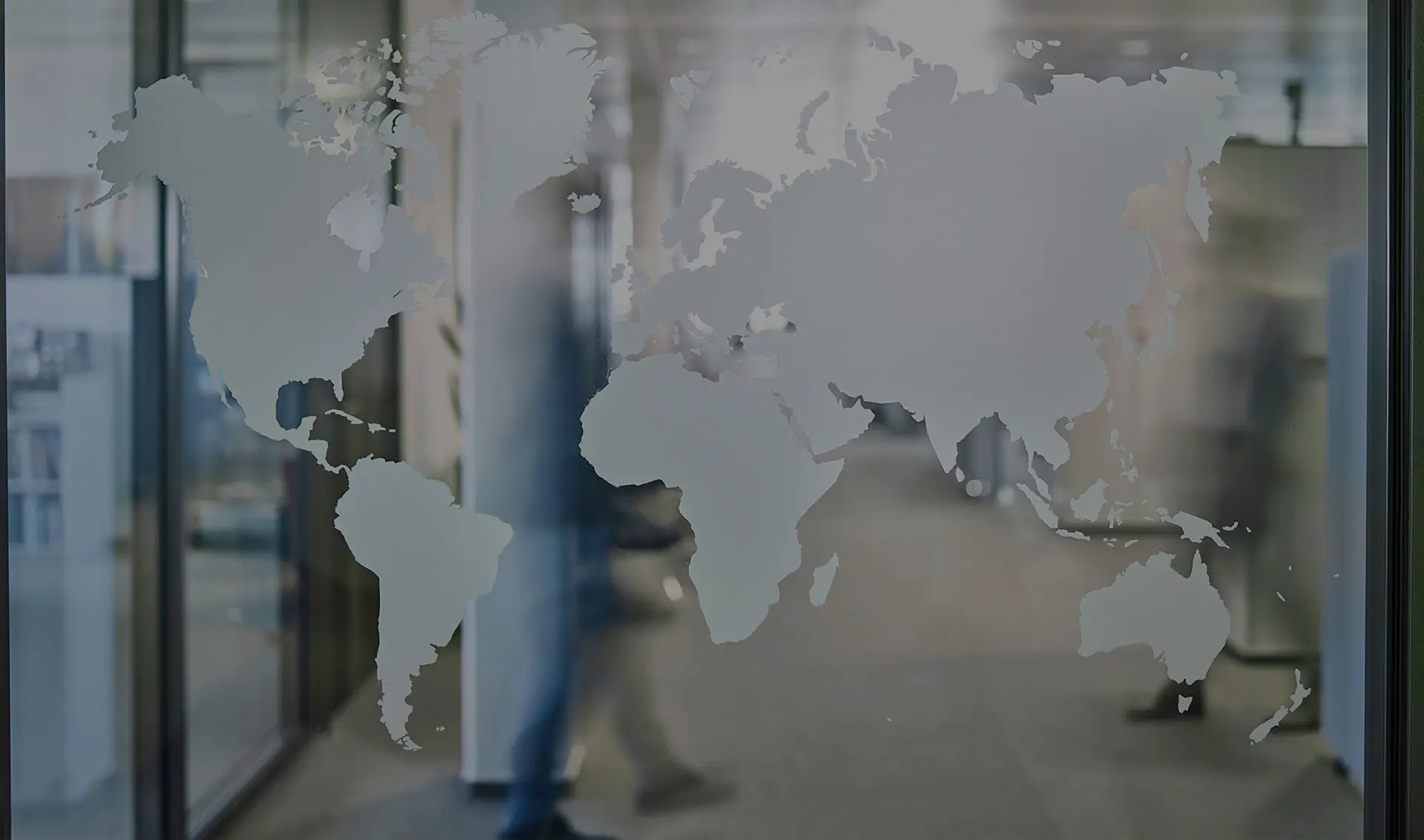 A world map made of frosted glass is mounted on the glass panel of an office door. You can make out the outlines of the continents.