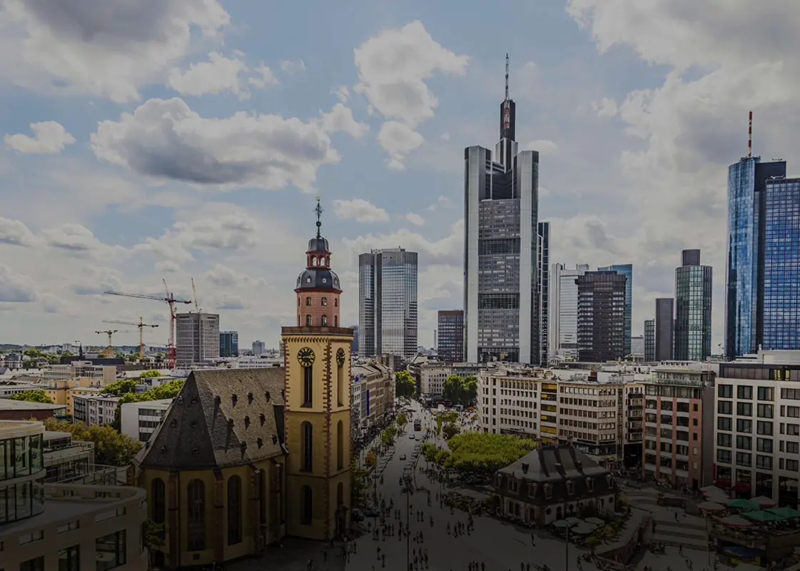 Überblick über eine Stadt mit einer alten Kirche vor Hochhäusern unter einem bewölkten Himmel.
