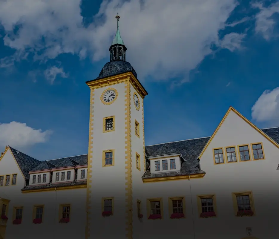 Ein historisches Gebäude mit einem gelben Uhrturm und blauem Himmel im Hintergrund.