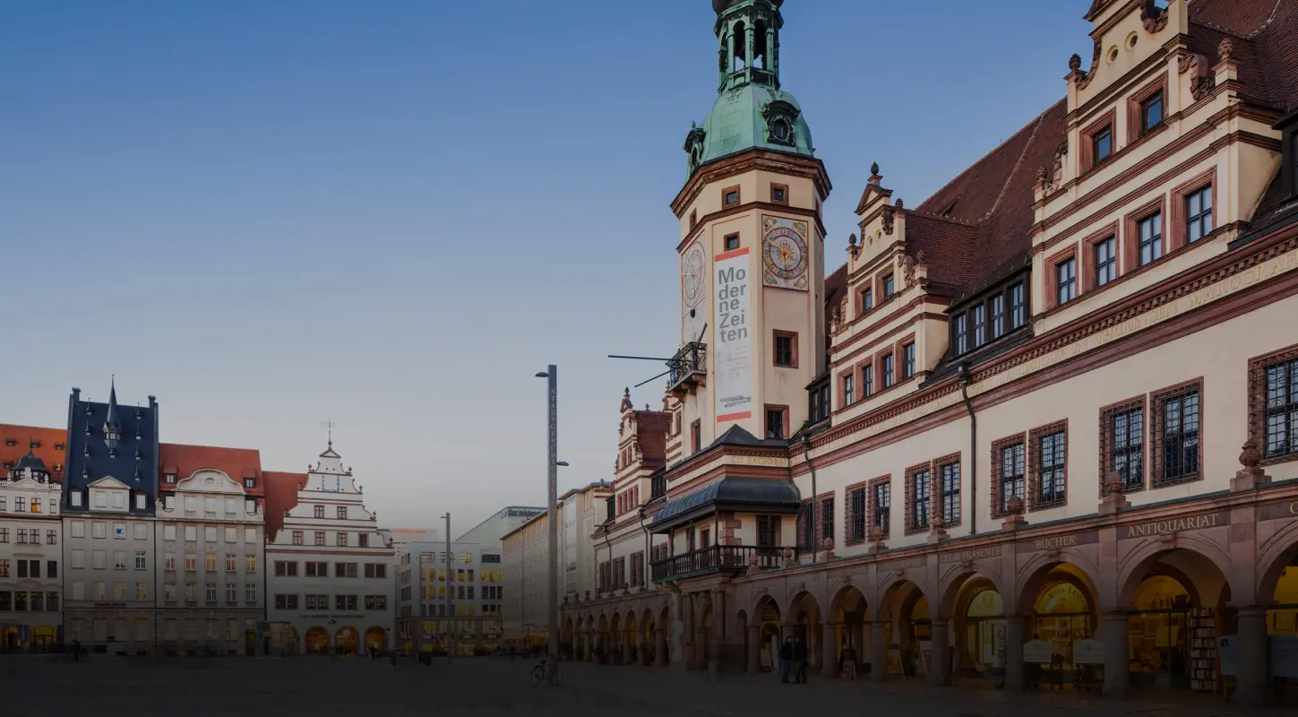 Ein Rathaus und umgebende Gebäude in einer europäischen Stadt bei Sonnenuntergang.