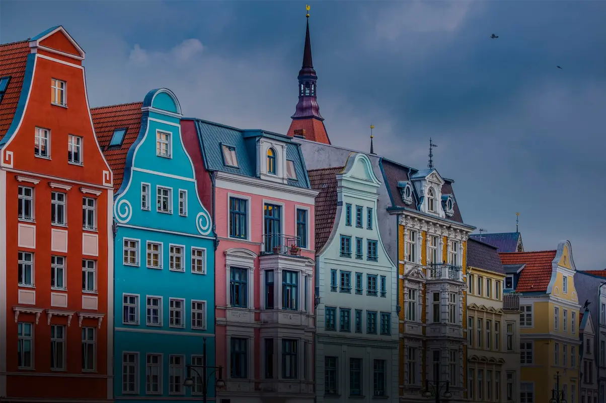 Bunte Stadthäuser mit barocken und neoklassischen Fassaden reihen sich an einer Straße.