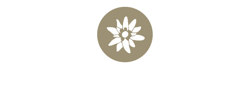Weiße stilisierte Alpenblume mit elf Blütenblättern auf rundem goldenem Hintergrund. Form erinnert an ein Edelweiß.